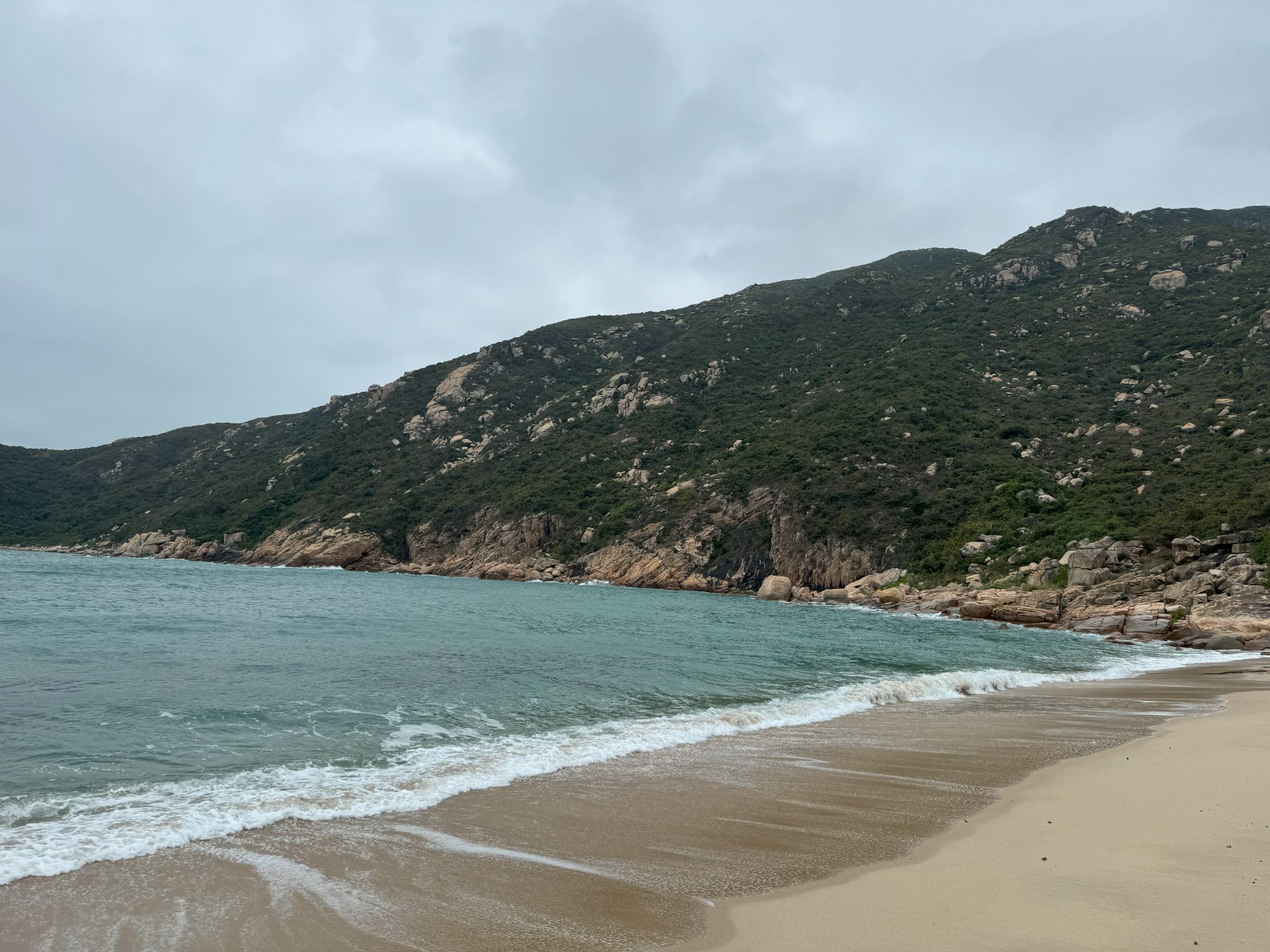 A quiet beach backed by green hills on Lamma Island